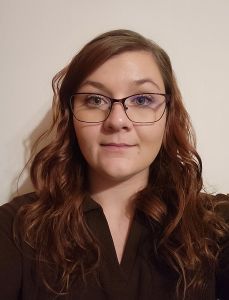 a lady in her late 20s with auburn hair and glasses